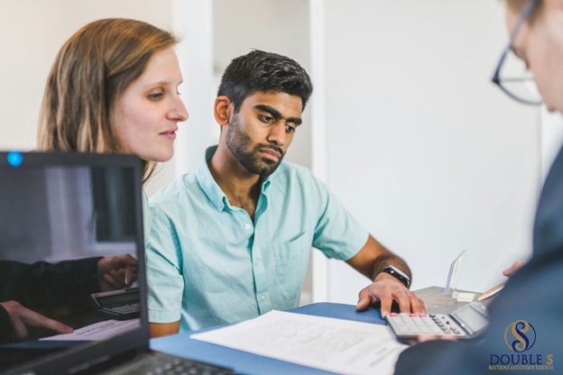 Two people use a laptop and calculator for a financial discussion