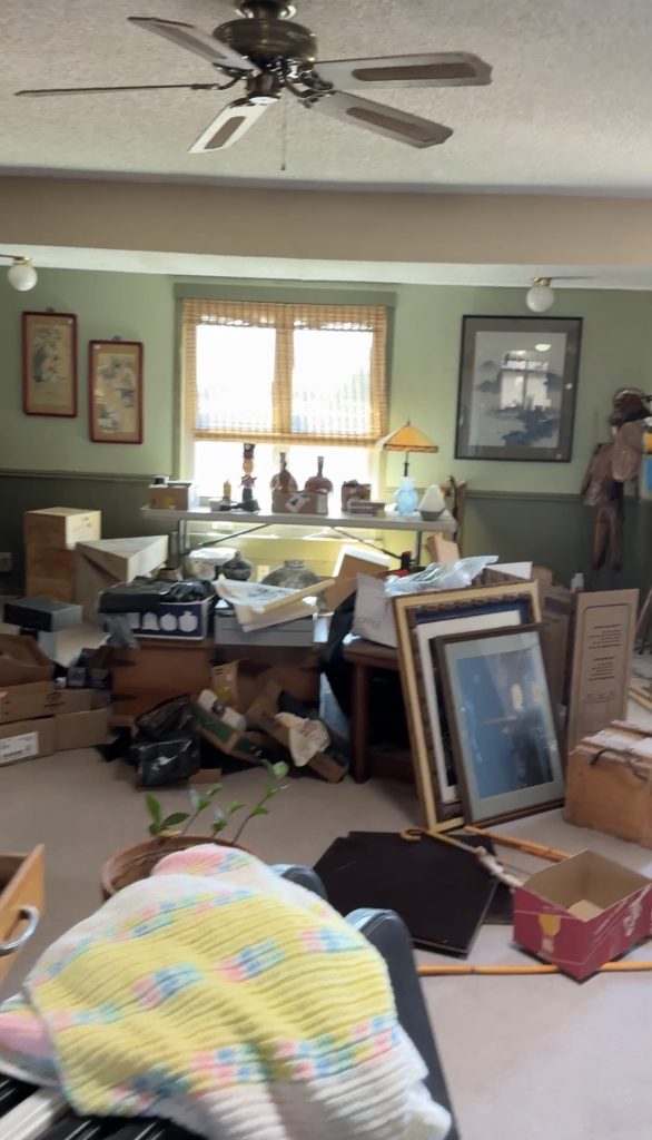 A room packed with boxes, framed art and furniture before the cleanout